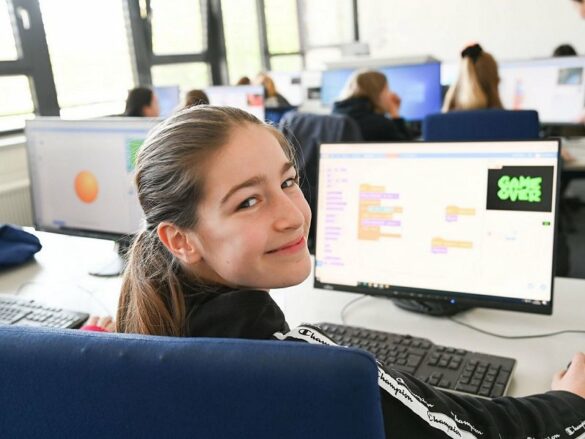 FH_GD_2023-programmierung Ein Mädchen blickt lächenld über die Schluter und erfreut sich am Programmierergebnis.