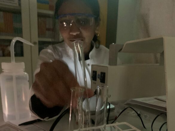 wwu-chemie-10 Ein Mädchen mit Schutzbrille hält ein Reaganzglas.