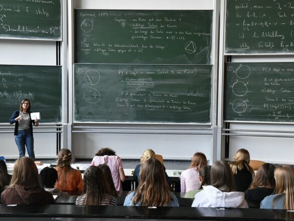 wwu-mathe-GirlsDay-231 Die teilnehmenden Schülerinnen sind in einem Hörsaal mit großen beschriebenen Tafeln.