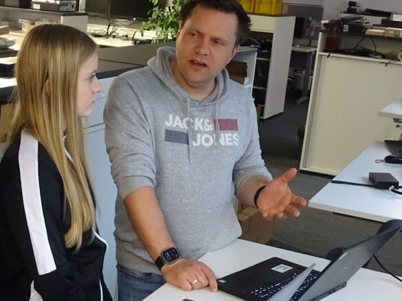 girlsday-2024-westfalen-ag-4 Ein männlicher Mitarbeiter erklärt einen Mädchen etwas zur IT.