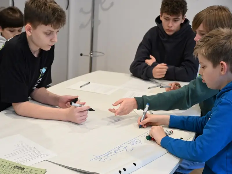 boysday-2026-Personalamt-2 5 Jungen sitzen um einen Tisch und schreiben gemeinsam.