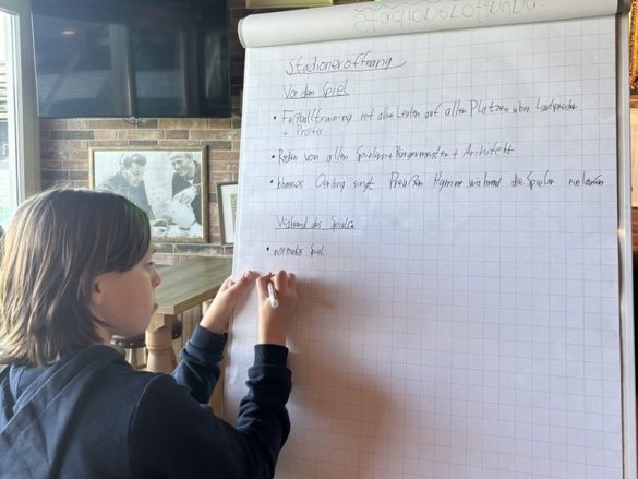 Eine Schülerin beschriftet eine Flipchartseite